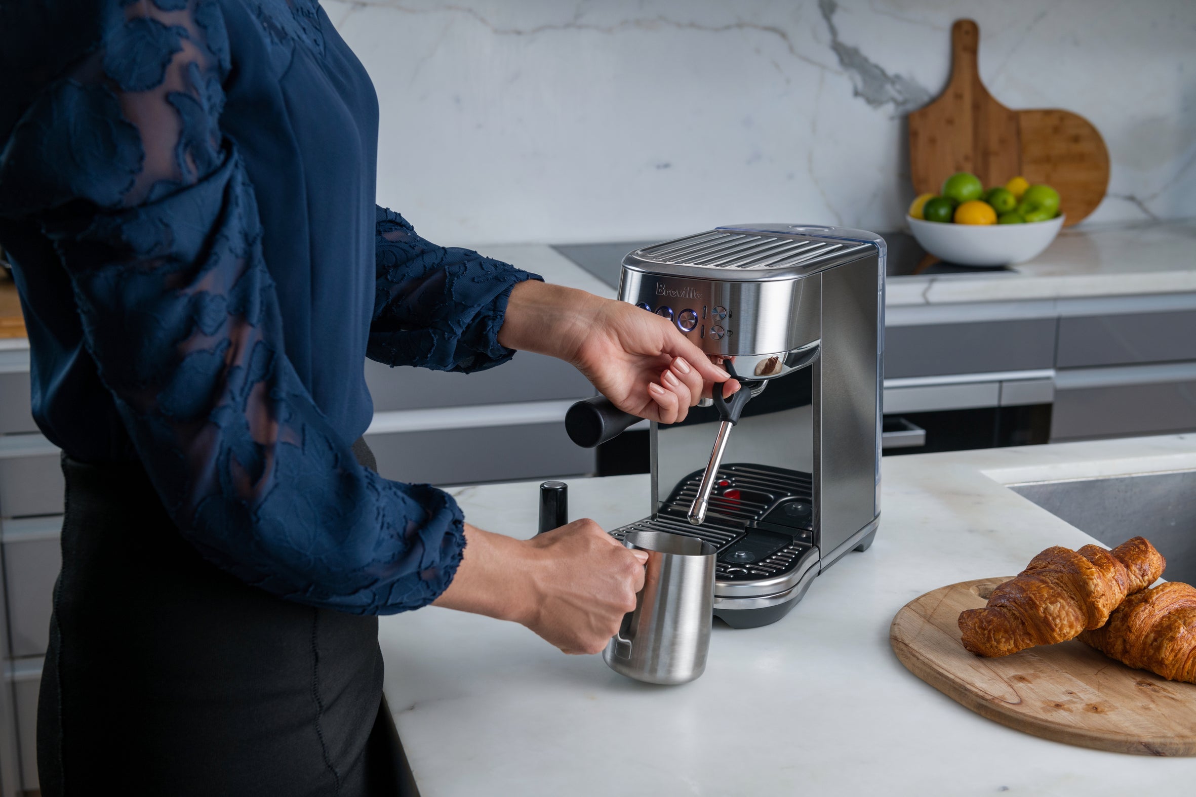 Real product photography: a person operating the Breville Bambino Plus and steaming milk